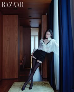 the woman is posing in her room wearing black stockings