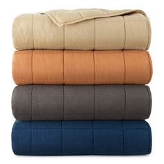 four blankets stacked on top of each other in different colors and sizes, with one folded up