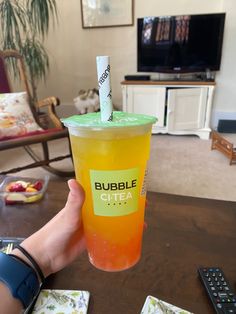 a person holding up a cup with a straw in it that says bubble city on the side