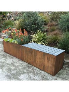 a wooden bench sitting in the middle of a garden filled with flowers and plants on top of cement ground