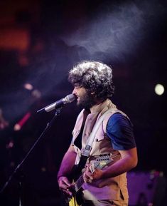 a man with curly hair playing guitar on stage