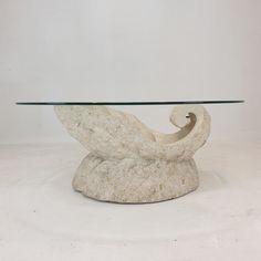 a white table with a glass top and an animal sculpture on it's base