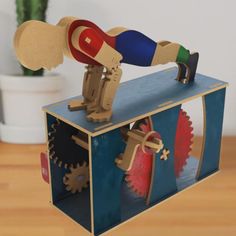 a wooden toy that is on top of a box with gears and wheels in it