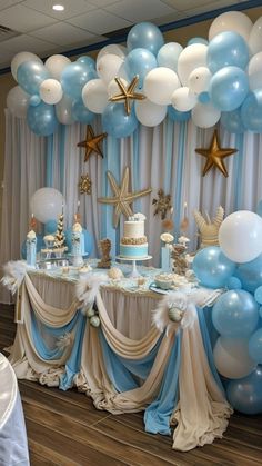 a table topped with blue and white balloons next to a wall covered in gold stars