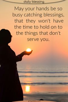 a woman holding a candle in her hand with the sun setting on the beach behind her