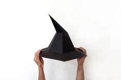 a person holding up a black paper hat