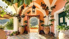 an arched doorway with potted plants on either side and a lantern hanging from the ceiling