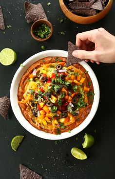 a bowl of nachos with tortilla chips and salsa on the side