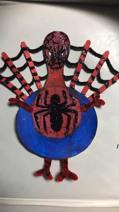 a paper mache depicting a spider man on a blue plate with red and black stripes