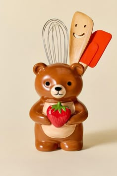 a brown bear holding a strawberry and whisk