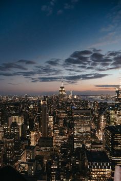 the city skyline is lit up at night, with skyscrapers in the foreground