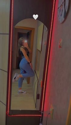 a woman standing in front of a mirror with her leg on the wall and looking at herself