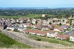 an aerial view of houses on a hill overlooking the city and fields in the distance