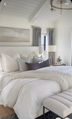 a white bed sitting in a bedroom next to a window