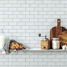 bread, milk and other kitchen items on a shelf in front of a white brick wall