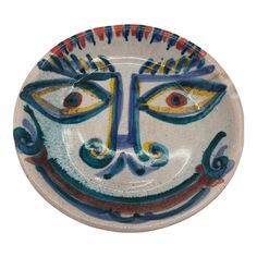 a ceramic plate with an artistic face painted on the front and sides, in multicolored colors