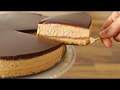 a person is cutting into a chocolate and peanut butter cheesecake on a cake plate