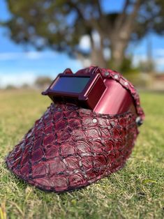 an electronic device sitting on top of a red bag in the middle of some grass