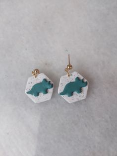 two small white and green earrings on top of a table