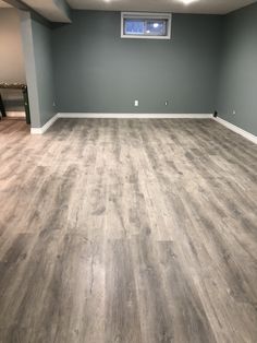 an empty room with hard wood flooring and gray walls in the corner is shown