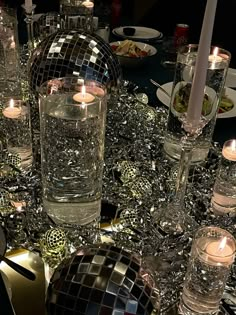 a table topped with lots of glass vases and candles