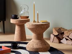 a table with two candles on top of it next to some logs and a cup