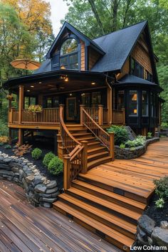 a wooden deck with steps leading up to a large house in the middle of trees