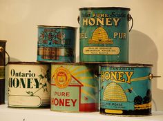 several tins of honey are stacked on top of each other in different colors and sizes