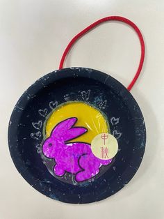 a paper plate with an image of a rabbit painted on it and a red string