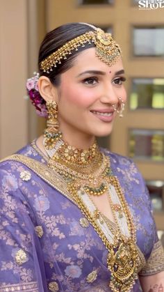 a woman in a purple sari with gold jewelry on her neck and headpiece