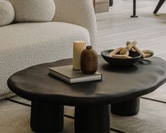 a living room with a couch, coffee table and books on the floor in front of it