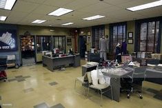 an office filled with lots of desks and people standing in the room next to them