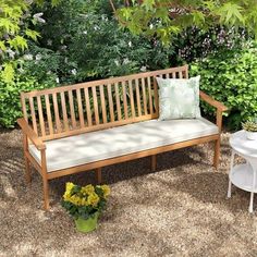 a wooden bench sitting in the middle of a garden next to a potted plant