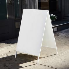 a white sign sitting on top of a sidewalk