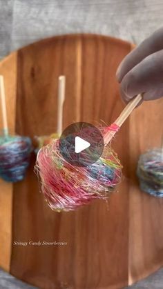 a person is holding some lollipops on a stick with yarn in them