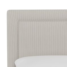 the headboard of a bed with white and grey striped sheets on it, against a white background