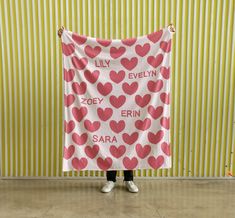 a person standing in front of a wall holding up a pink and white heart - shaped banner