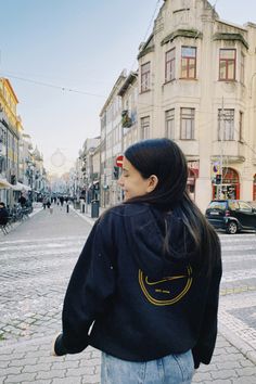 a woman is walking down the street with her back to the camera