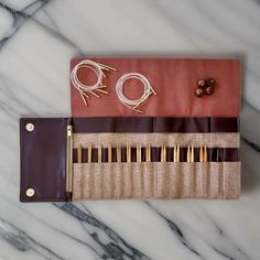 an assortment of knitting needles in a case on a marble table with pins and needles