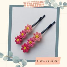 two pink and yellow flower hair clips on top of a piece of paper