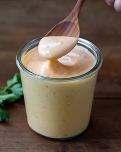 a spoon full of dressing on top of a wooden table