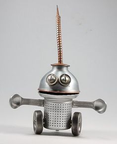 a metal robot with a screwdriver on it's head and eyes, sitting in front of a white background