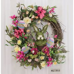 a wreath with flowers and an easter bunny on it hanging from the front door,