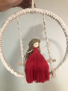 a small doll hanging from a rope in a circular ornament on a wall