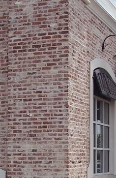 a red fire hydrant in front of a brick building with white trim and windows