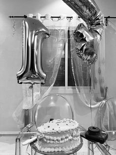 black and white photograph of a birthday cake with balloons in the shape of an i - letter