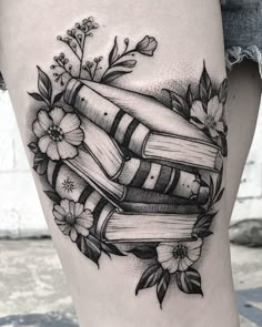 a woman's thigh with books and flowers on it