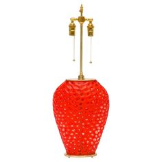 a red vase sitting on top of a white floor next to a lamp with two lights