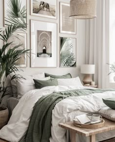 a bed with white sheets and green pillows in a room filled with pictures on the wall