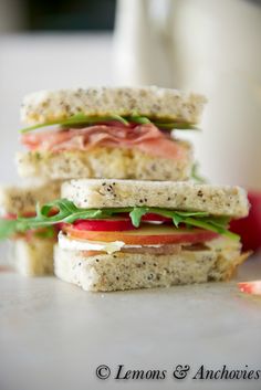 two sandwiches stacked on top of each other with tomatoes and lettuce in the middle